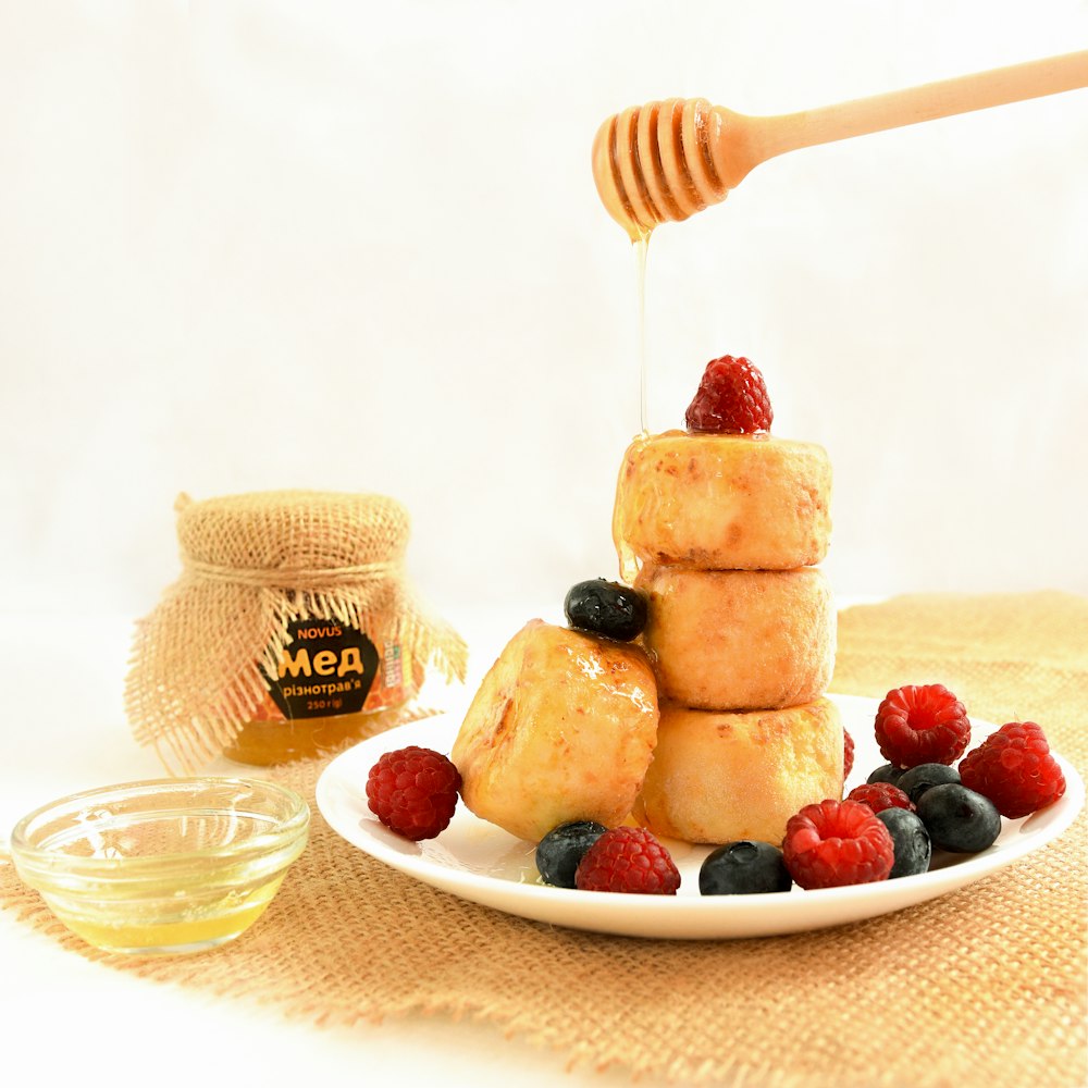 a plate of food with berries and a honey dip