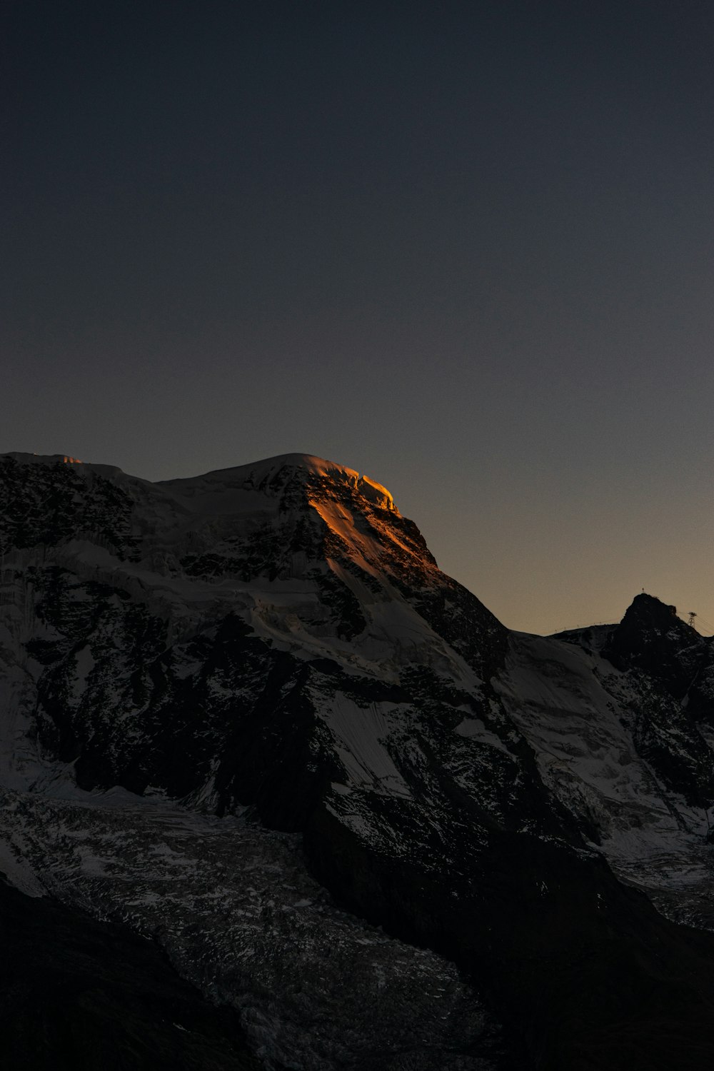 a very tall mountain covered in snow under a dark sky