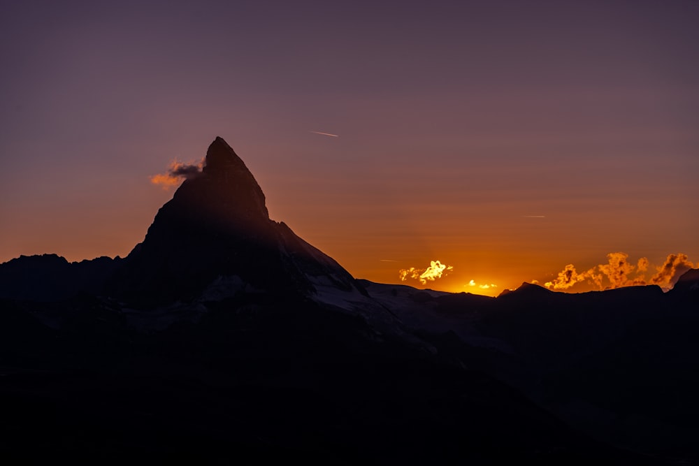the sun is setting behind a mountain peak