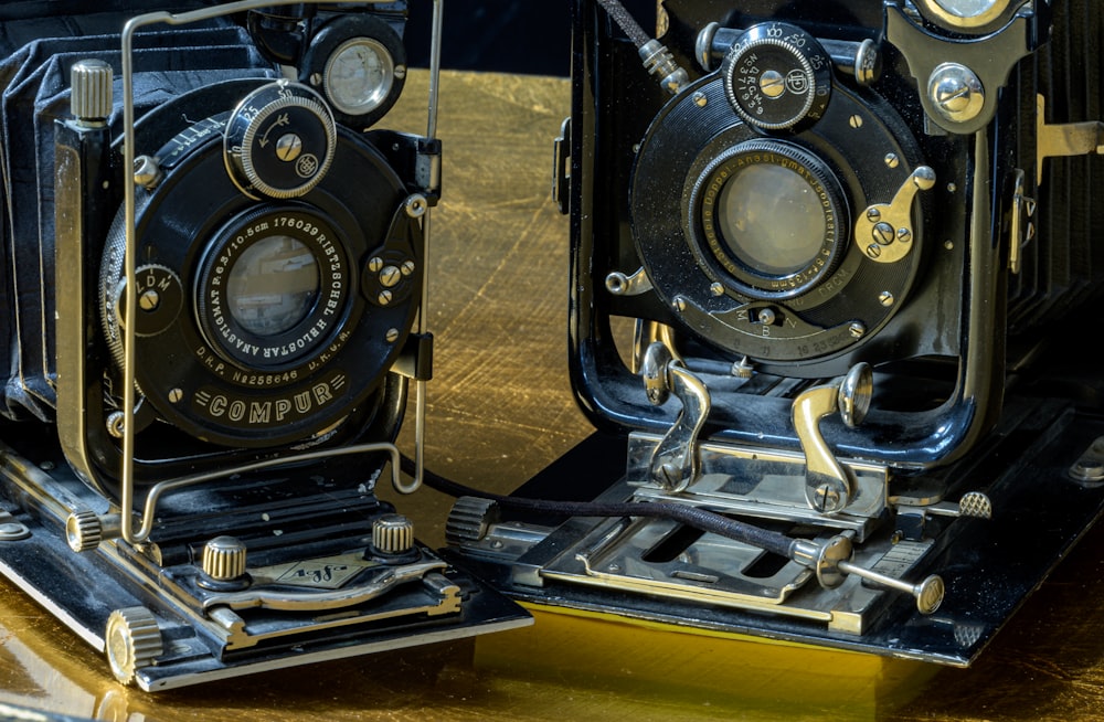 two old fashioned cameras sitting on top of a wooden table