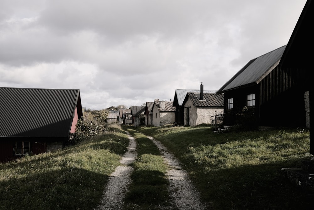 a dirt road between two buildings on a hill