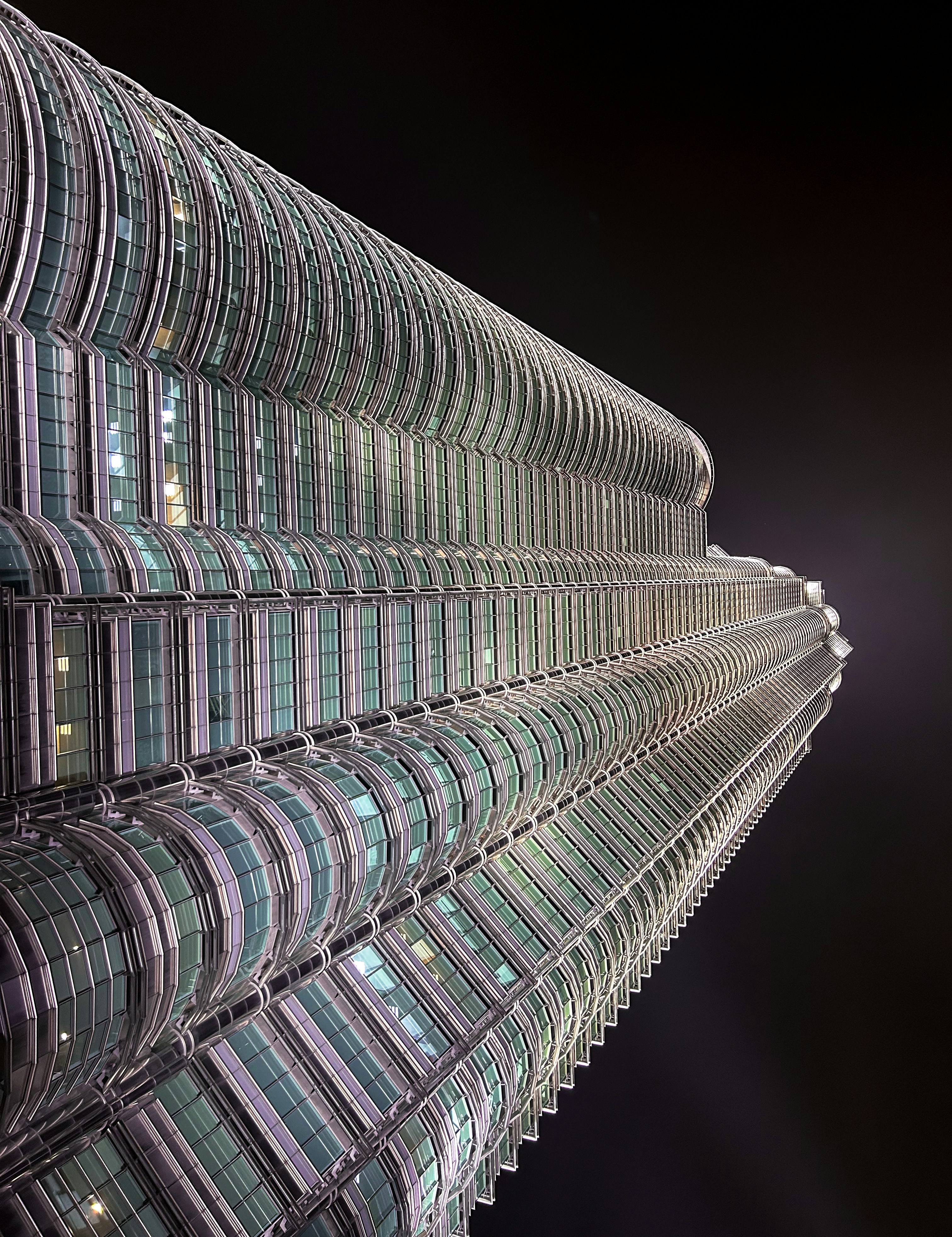Modern glass commercial tower at night, dark sky, dramatic lighting, financial district atmosphere