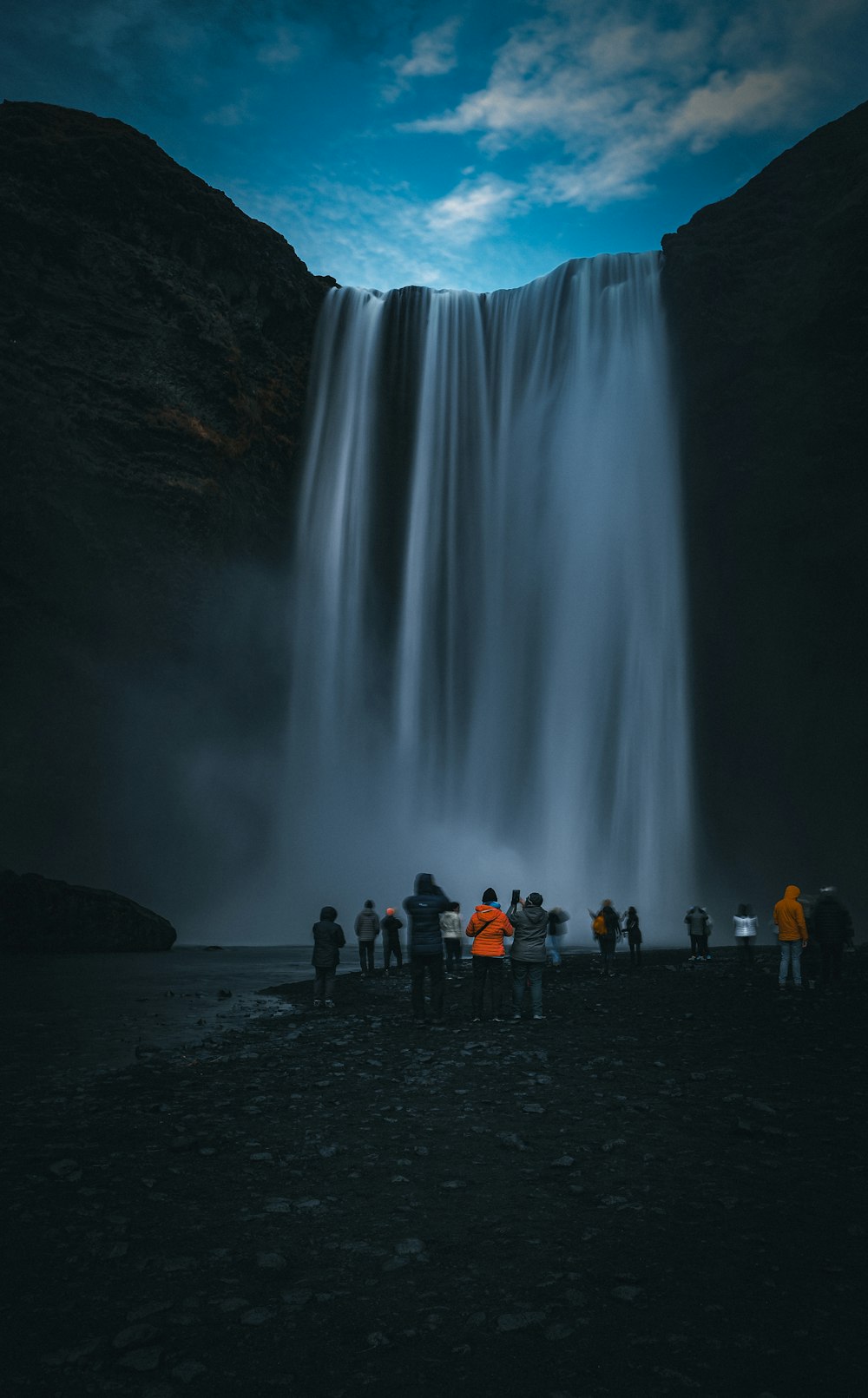 a group of people standing in front of a waterfall