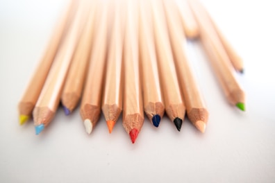 Close-up of vibrant colored pencils fanned out on a white background.