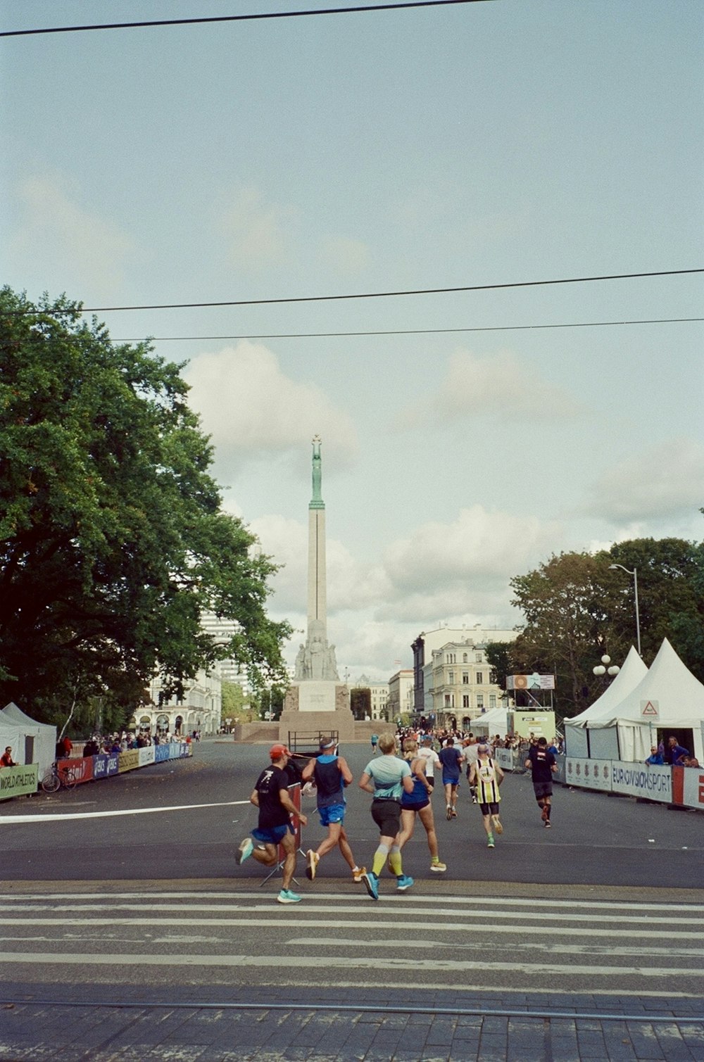 a group of people crossing a street in front of a monument