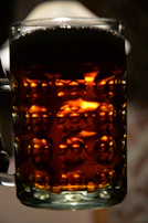 A Viking horn mug filled with frothy ale, held by a person wearing a woolen sleeve.