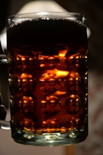 Close-up of a frothy craft beer glass held against the warm ambiance of Dorf Brewhouse.