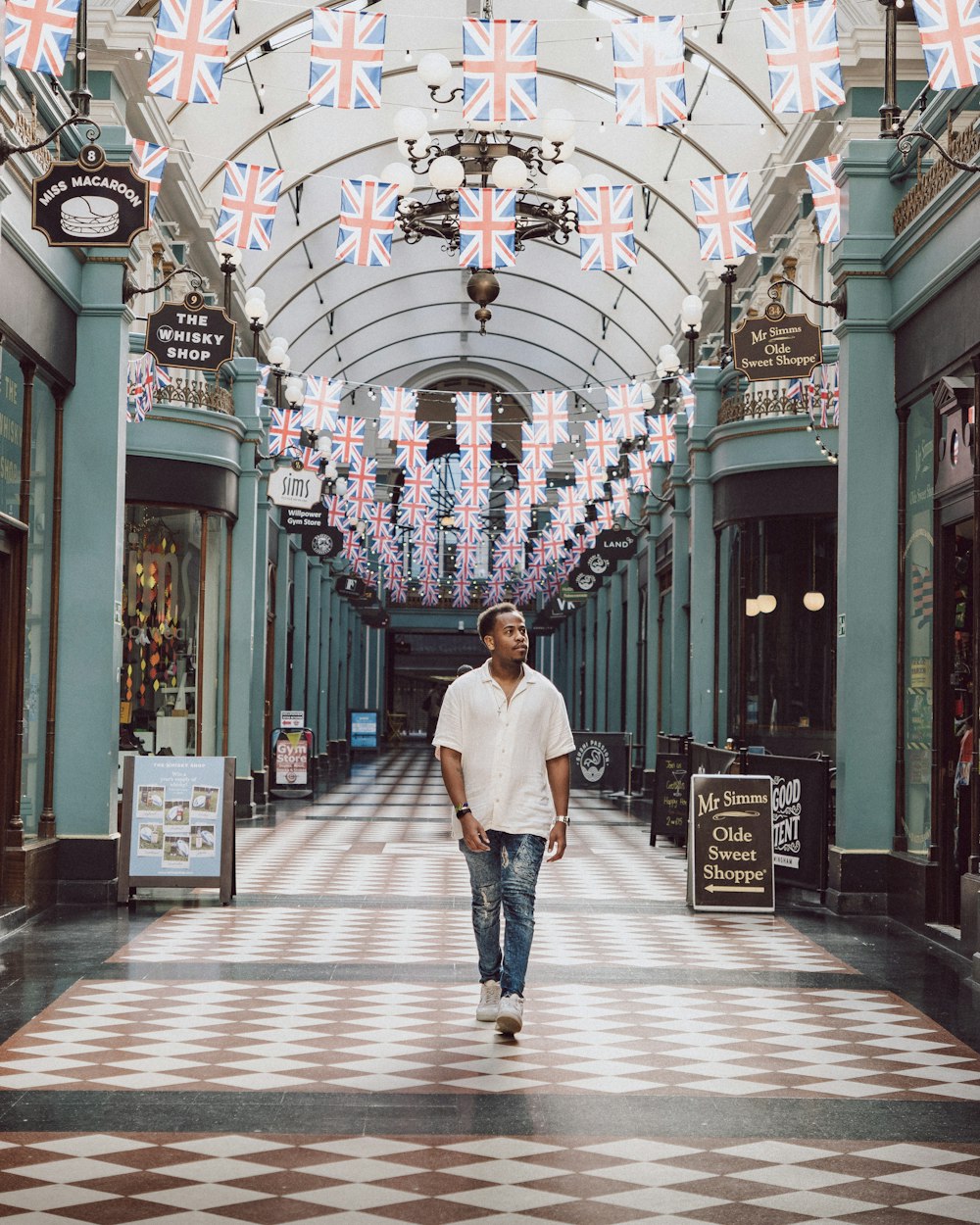 a man walking down a hall with flags hanging from the ceiling