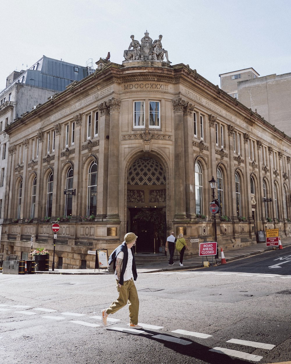 a man walking across a street in front of a building