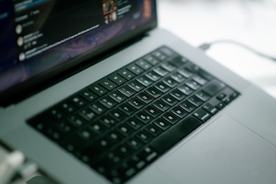 Close-up of hands typing on a laptop with messaging app interfaces visible on the screen.