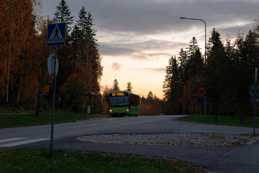 Un autobús verde que circula por una calle junto a un bosque