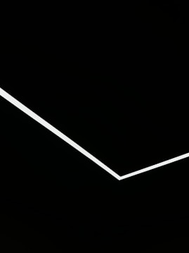 A minimalist design featuring a single white angular line traversing a black background, creating a stark contrast and geometric aesthetic.