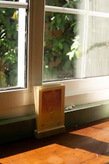 A calendar and a set of keys resting on a wooden desk by a sunny window.