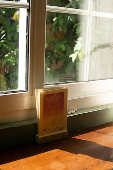 A calendar and a set of keys resting on a wooden desk by a sunny window.
