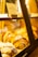 A display case filled with freshly baked pastries, including swirled and powdered varieties. The lighting is warm, casting a golden glow on the baked goods. A sign labeled 'Banana Cake' is visible inside the case.