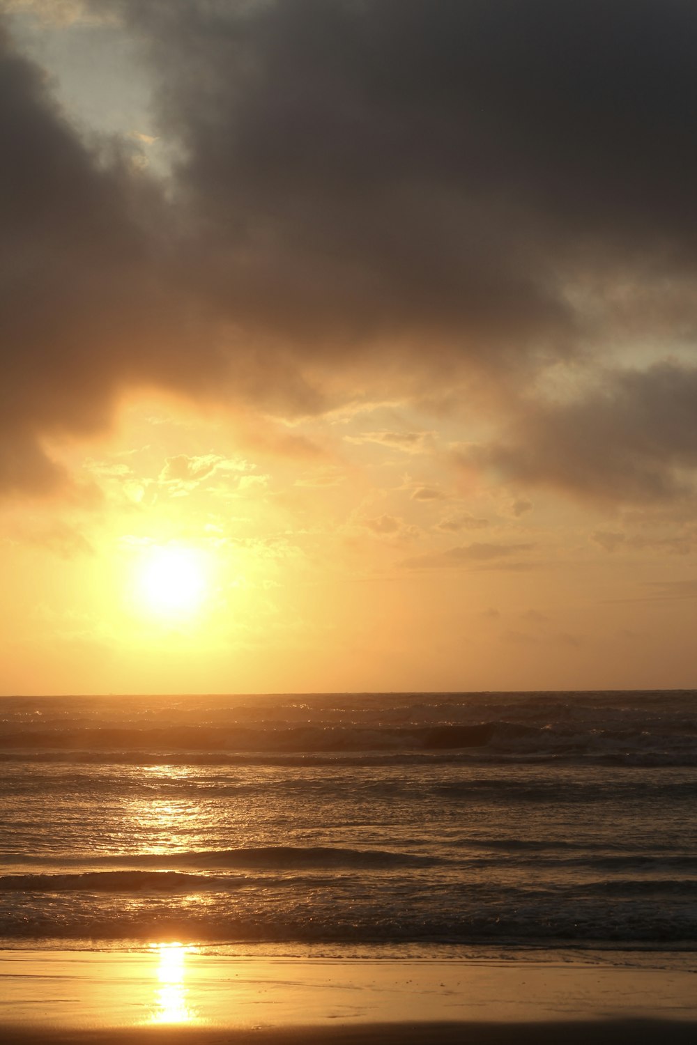 the sun is setting over the ocean on a cloudy day