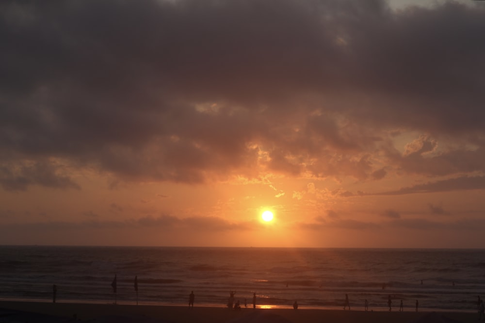 the sun is setting over the ocean on a cloudy day