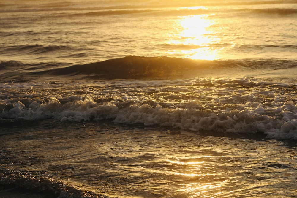 the sun is setting over the ocean waves