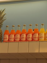 Rows of colorful juice bottles lined up on a rustic wooden shelf in a sunlit room.