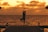 A group practicing yoga on a wooden deck overlooking the ocean at sunrise.