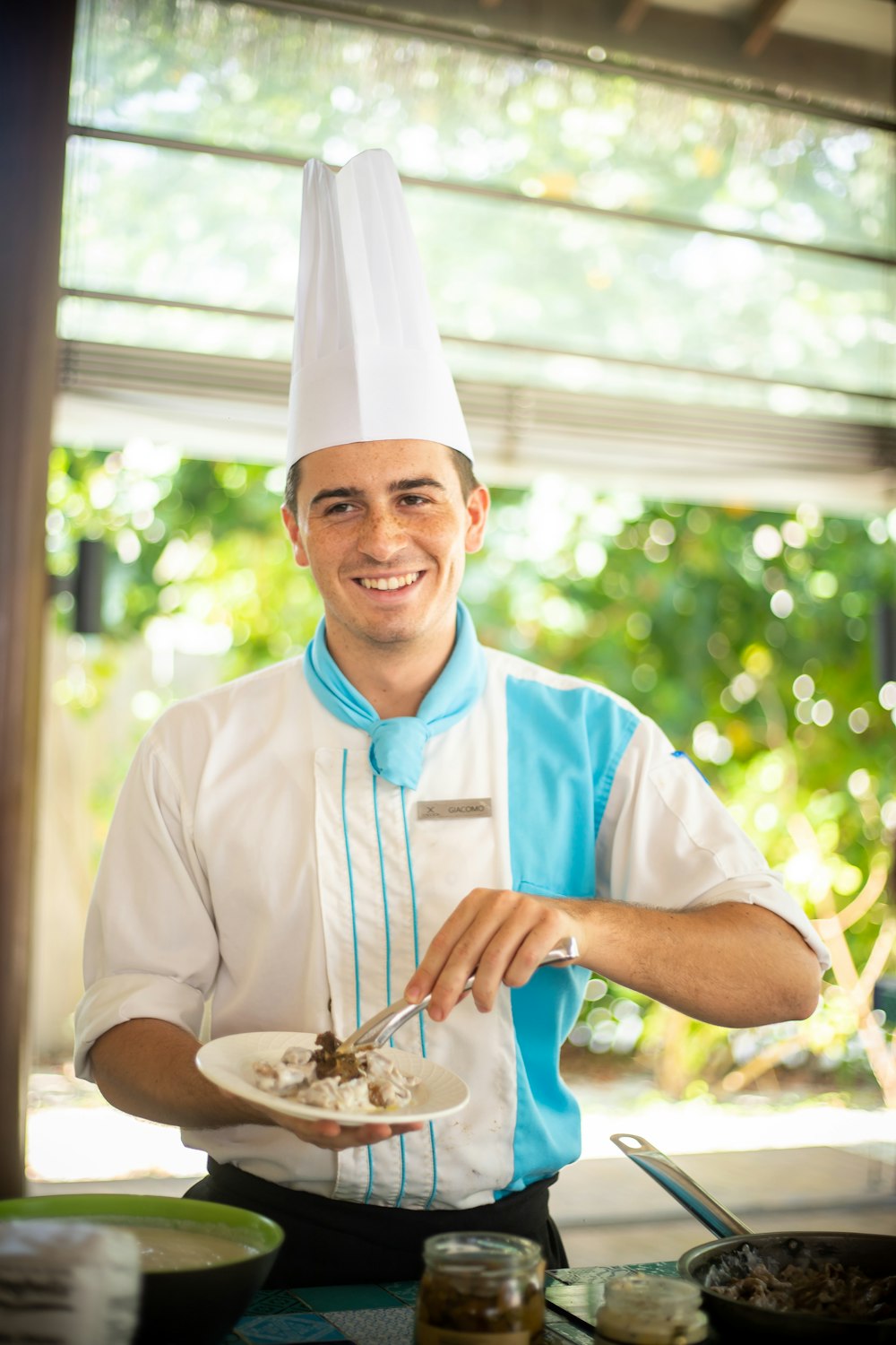 un homme dans une toque de chef tenant une assiette de nourriture