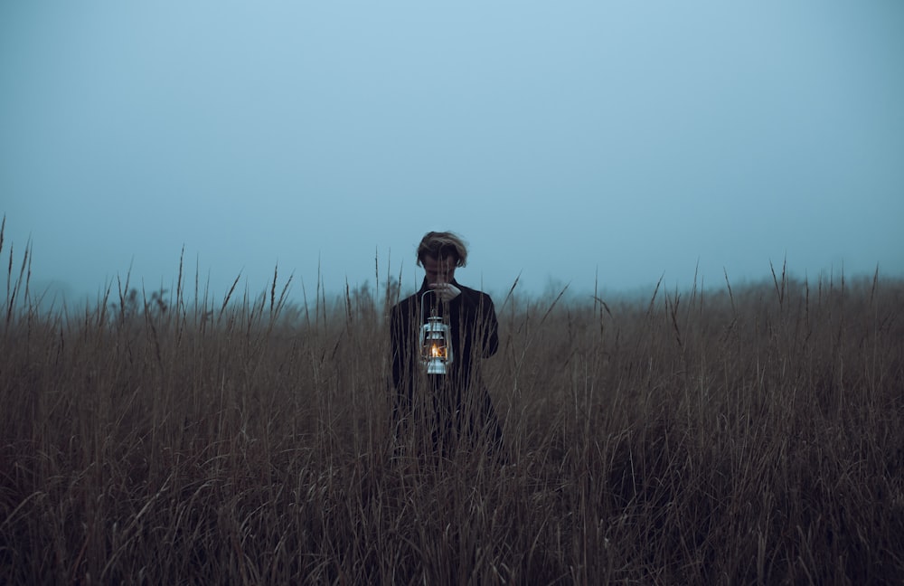 a person standing in a field holding a lantern