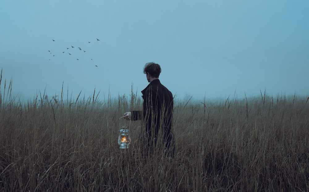 a man standing in a field holding a lantern
