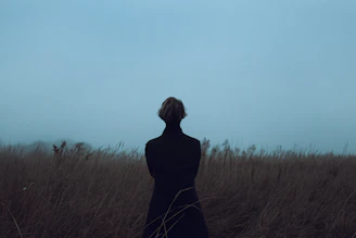 a woman standing in a field of tall grass