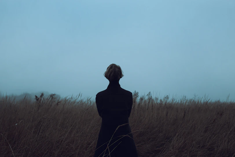 a woman standing in a field of tall grass