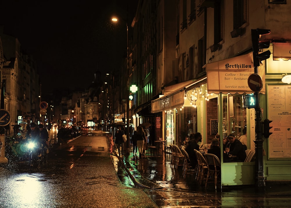 a city street at night with people sitting at tables