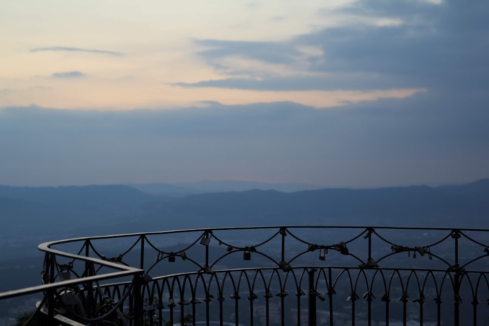 a metal railing with a view of mountains in the distance