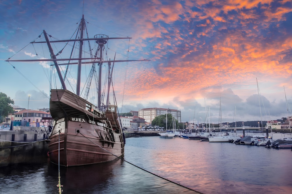 a boat docked in a harbor with a sunset in the background