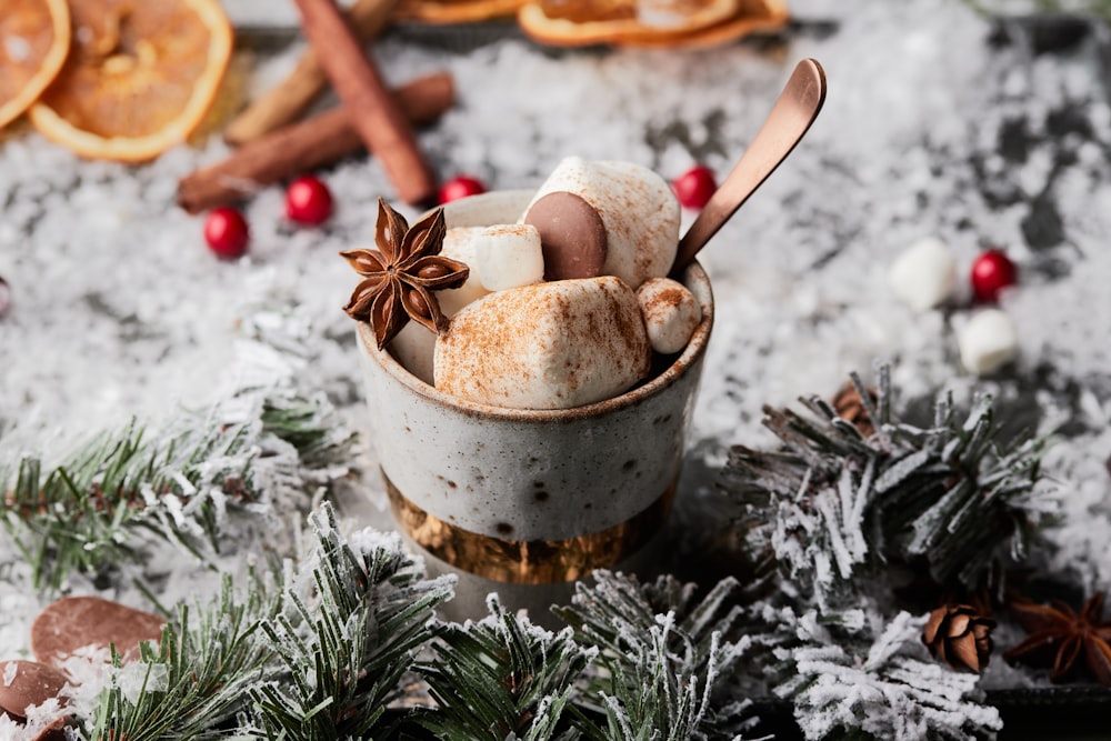 a cup filled with marshmallows, cinnamon, star anise, and