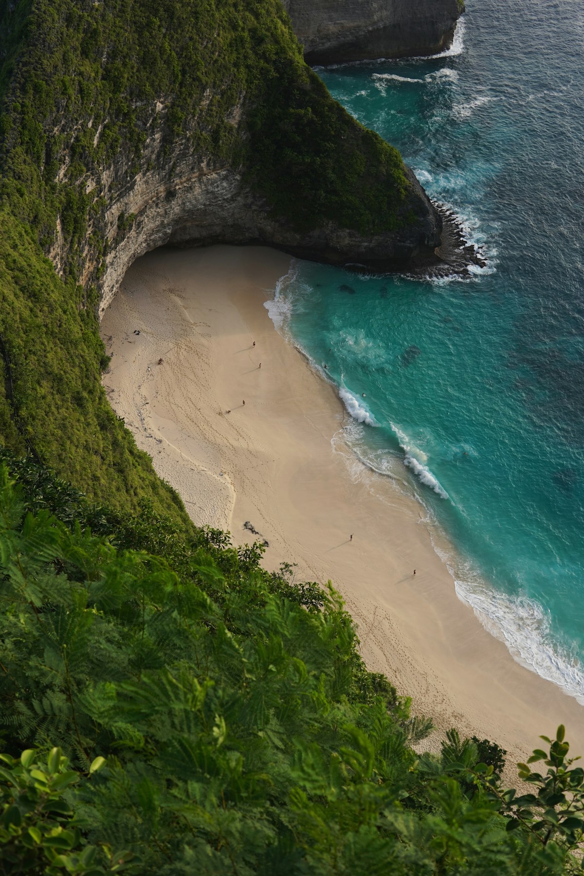 Nusa Penida November — dramatic sandy beach below cliffs in the early wet season