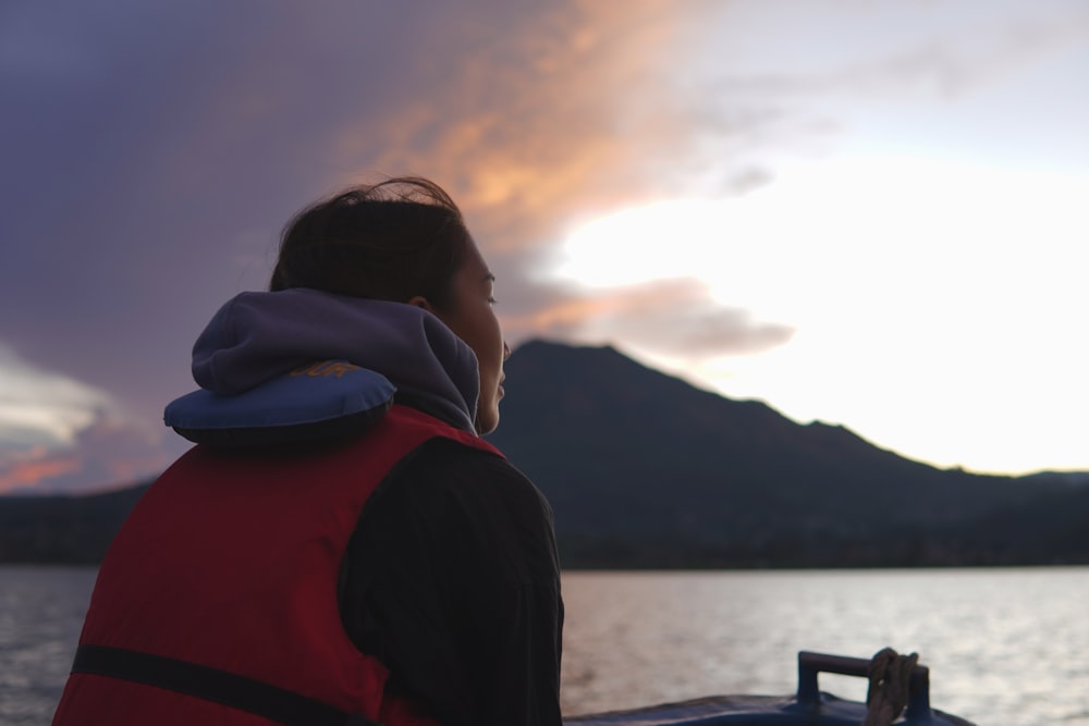 eine Person, die auf einem Boot sitzt und auf das Wasser blickt