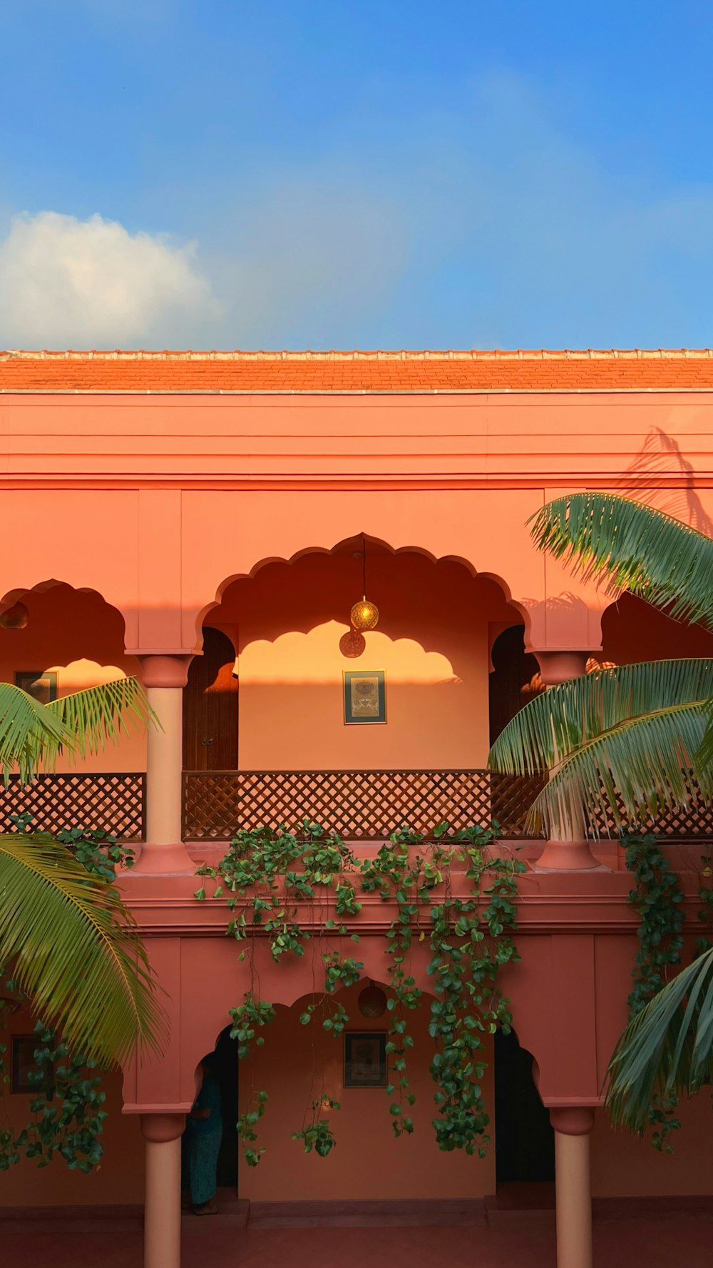 Un edificio rosa con balcón y palmeras