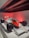 A vintage Formula 1 racing car with prominent red and white Marlboro and Shell branding is on display under a red light. The car features large black tires, a sleek aerodynamic body, and the number 1 displayed prominently on the front. The exhibit is set in a modern, minimalistic environment, enhancing the car's vibrant colors.