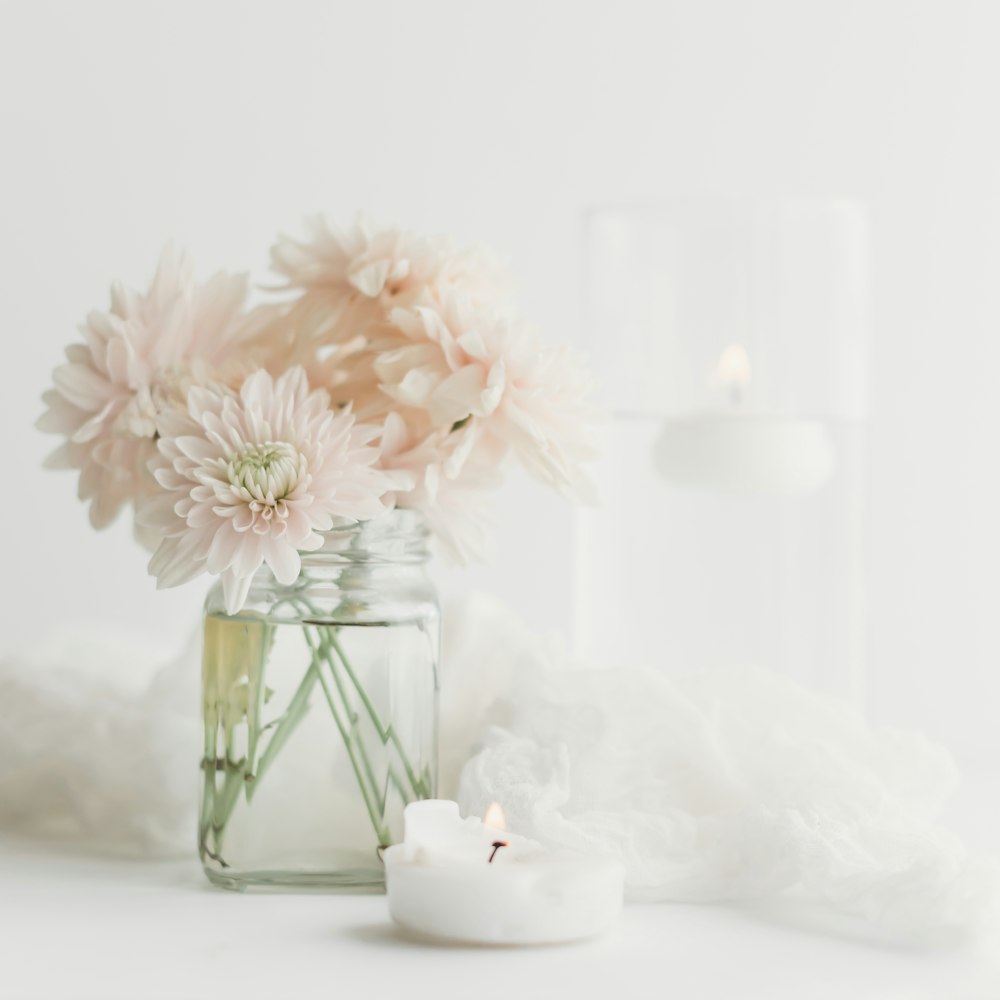 a vase filled with pink flowers next to a candle