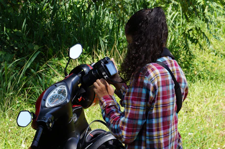 A person taking clear photos of a motorcycle outdoors with natural light.