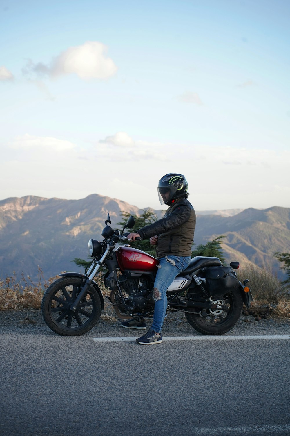 a man sitting on a motorcycle on the side of the road