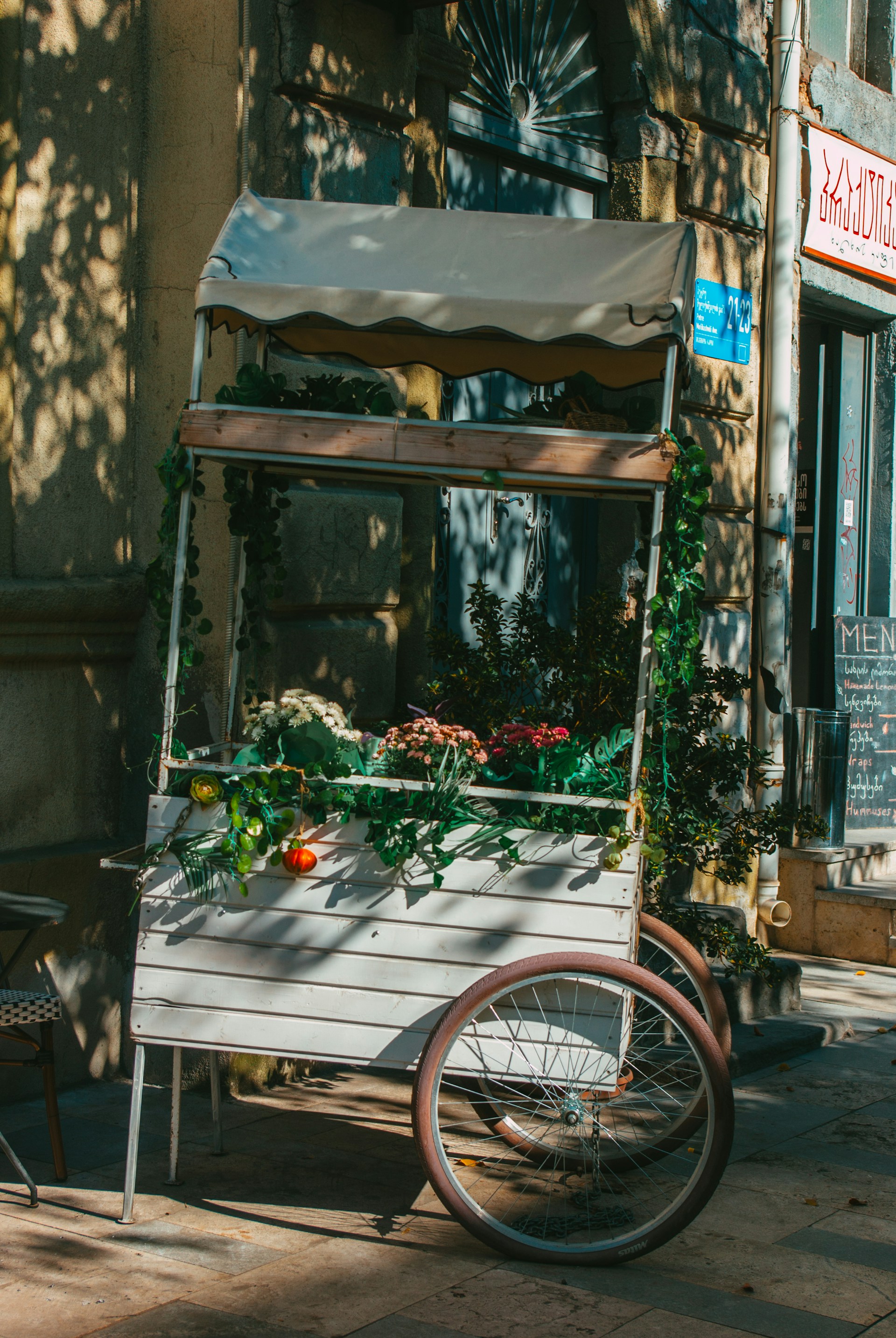 A charming vintage-style food cart decorated with fresh flowers at a sunny outdoor wedding in Valencia.