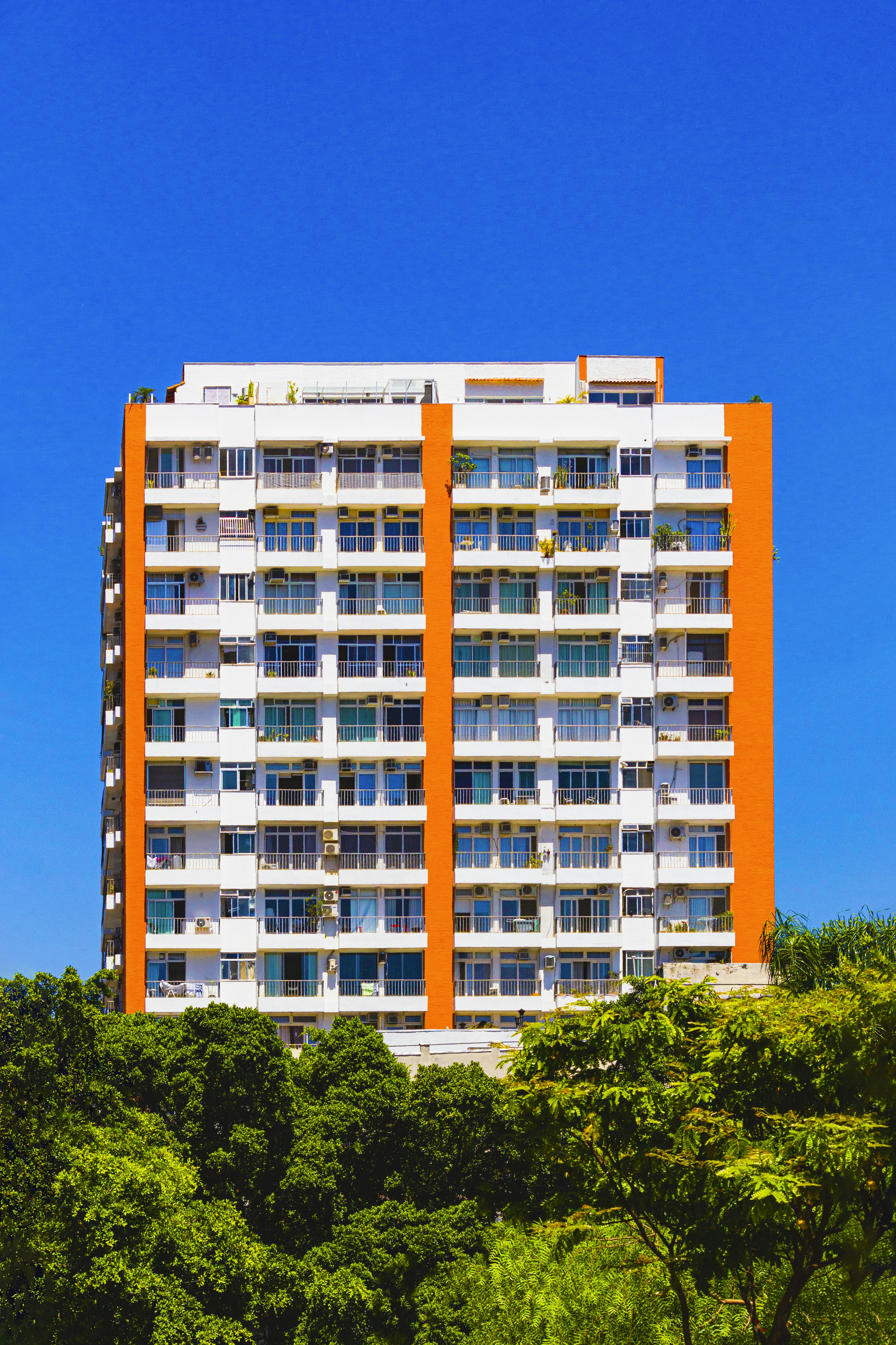 a tall white and orange building with trees in front of it