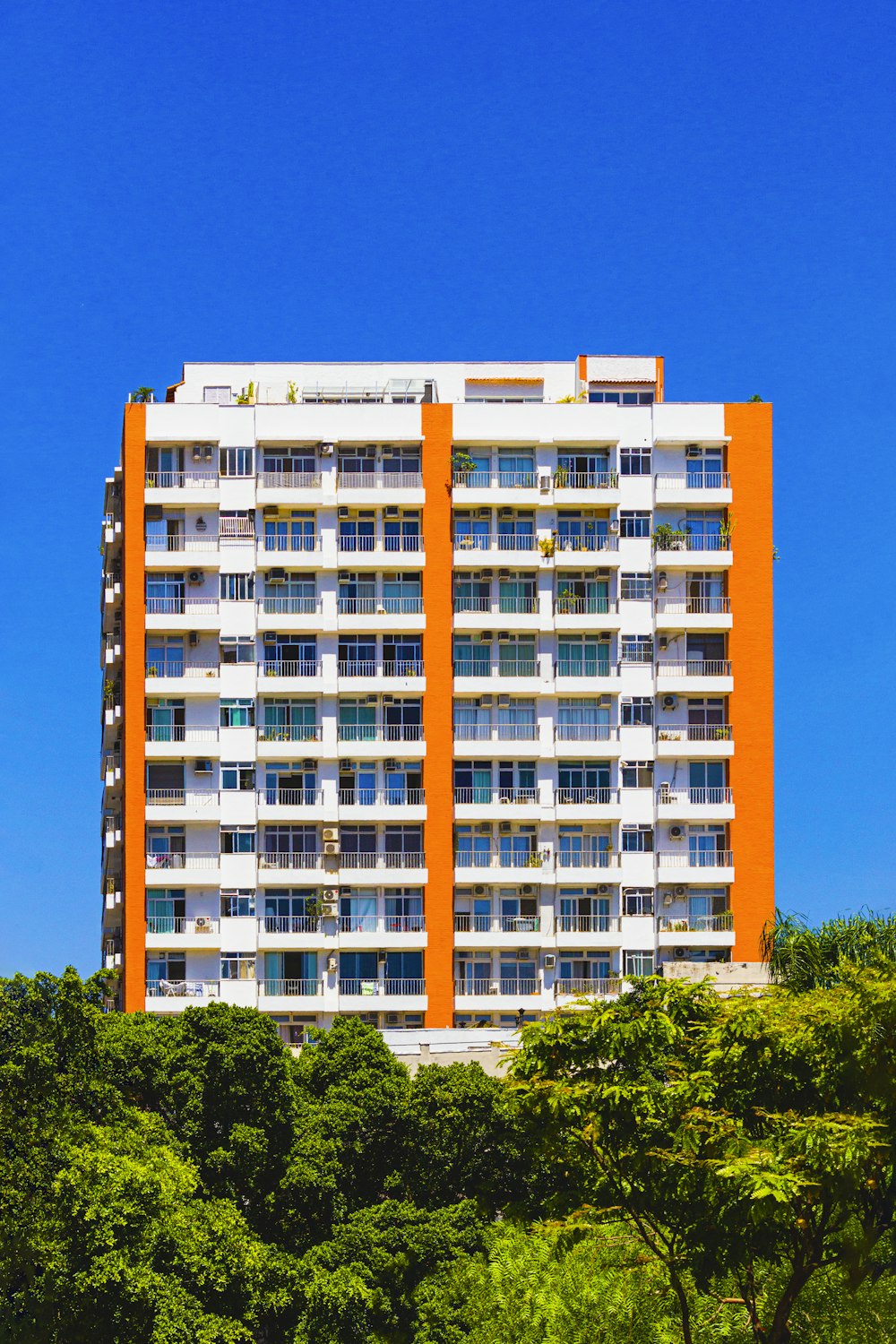 a tall white and orange building with trees in front of it