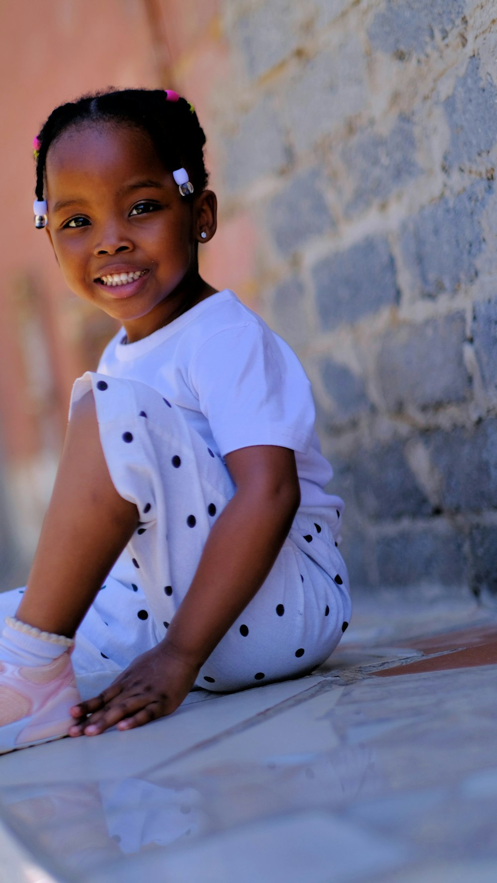 a little girl sitting on the ground smiling