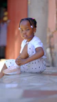 a little girl sitting on the ground with her feet crossed