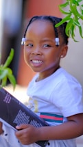 A friendly child holding a book in a bright classroom.