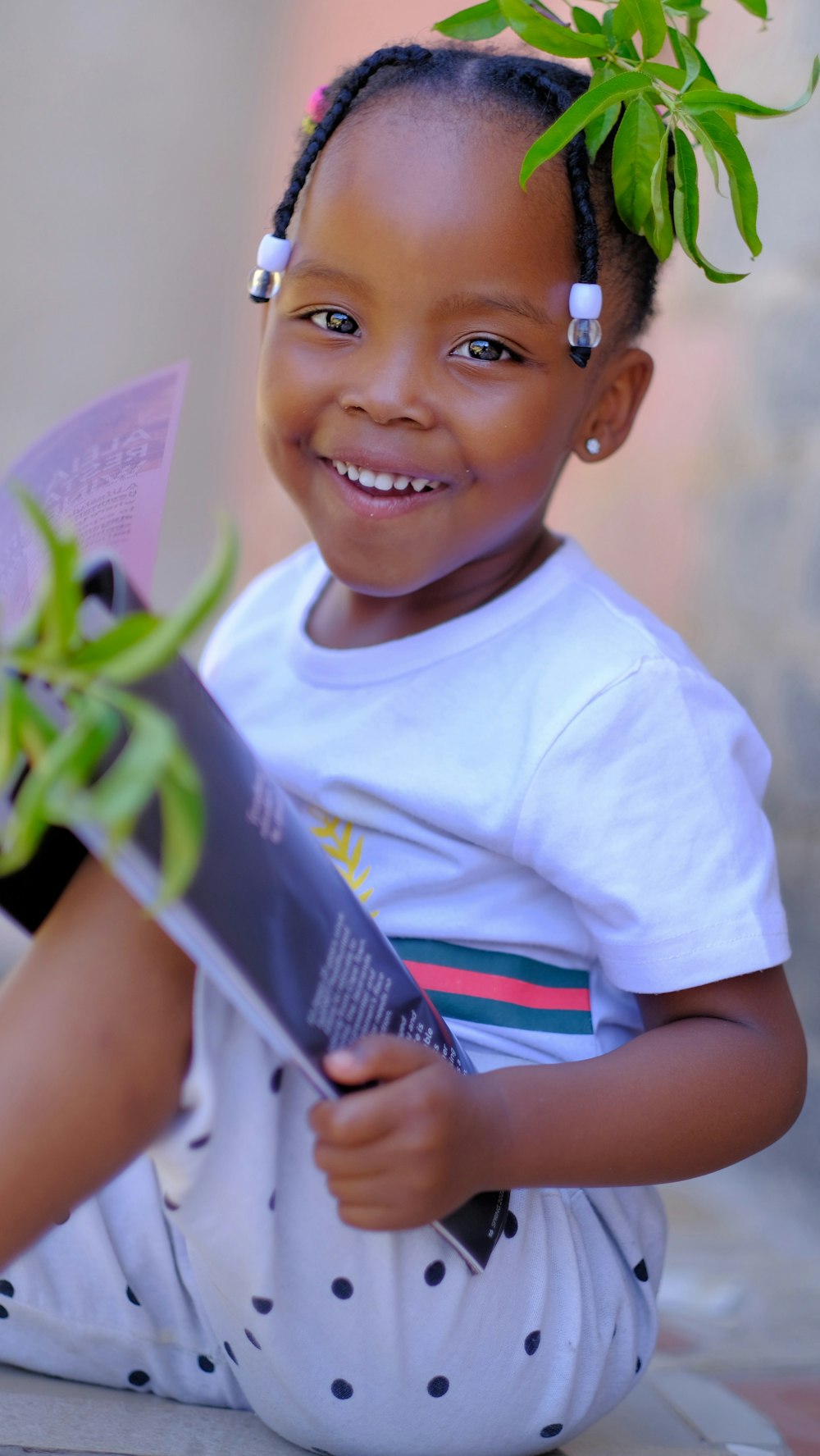 a little girl sitting on the ground with a plant in her hand