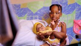 a young girl holding a baby in her arms
