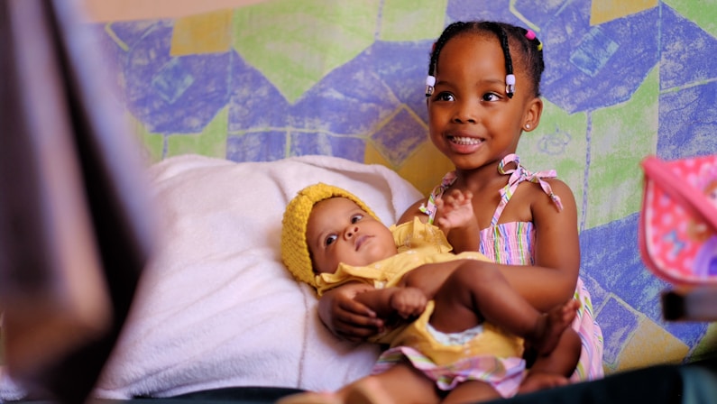 a young girl holding a baby in her arms