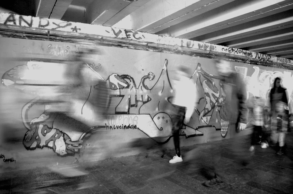 a group of people walking past a graffiti covered wall